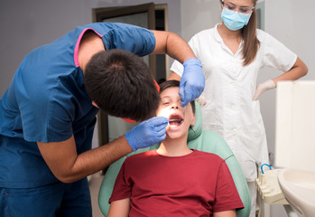 Boy with perfect teeth at the dentist doing check up with the clinic at the background - oral hygiene health care concept