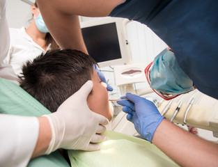 Boy with perfect teeth at the dentist doing check up with the clinic at the background - oral hygiene health care concept