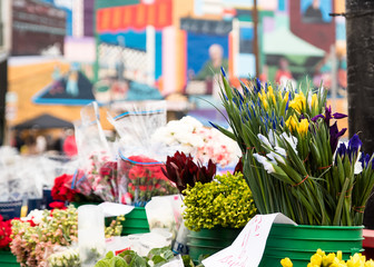 assorted flowers on a street market place with a colorful blurry mural  as a background ideal for flower signs or birthday cards