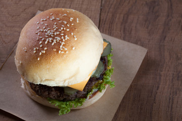 Close up of beef burger with cheese on wood table.