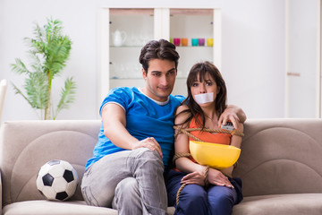 Man tying up his wife to watch sports football