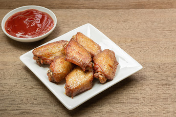 close up of hot and spicy baked chicken mid joint wing in a ceramic plate on wooden table. delicious appetizer menu