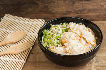 close up of fermented rice noodle with pork soup and vegetable in a ceramic bowl on old wooden table. vietnamese delicious food menu.