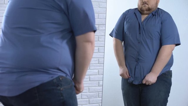 Plump man buttoning up tight shirt, oversize clothing problem, appearance
