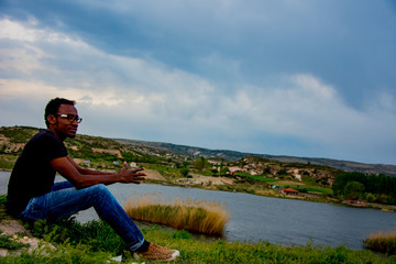 Fototapeta na wymiar Young black man posing on the lake coast