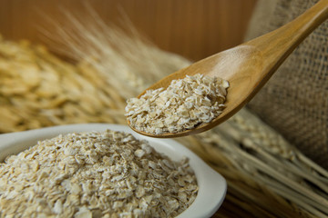 The Healthy breakfast cereal oat flakes in bowl on wooden table.