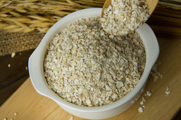 The Healthy breakfast cereal oat flakes in bowl on wooden table.