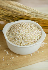 The Healthy breakfast cereal oat flakes in bowl on wooden table.