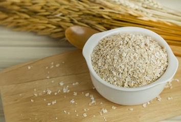 The Healthy breakfast cereal oat flakes in bowl on wooden table.