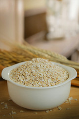 The Healthy breakfast cereal oat flakes in bowl on wooden table.