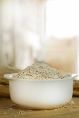 The Healthy breakfast cereal oat flakes in bowl on wooden table.