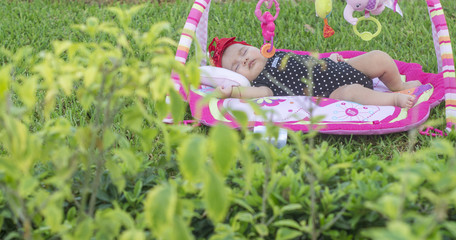 Beautiful baby, nice, tender emotions, lying on the grass, on pink carpet, playing in garden, happy laughing, black dress with white balls, in outdoor garden.