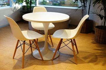 White round table and three comfortable chairs at the corner of the room with windows to the city...