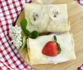 thin pancakes with berries on a wooden board - summer dessert