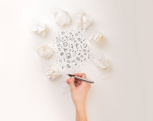 Female hand next to a few crumpled paper balls drawing mixed media icons