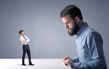 Young professional businessman being angry with an other miniature businessman 