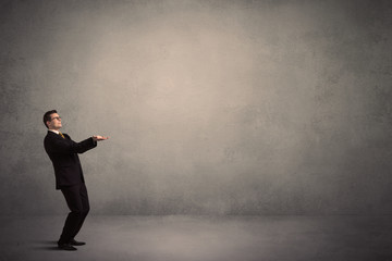 Fototapeta premium Caucasian businessman standing in front of a grunge, blank wall