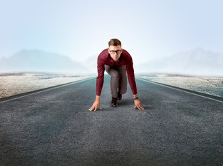 Young determined businessman kneeling before blank running track 