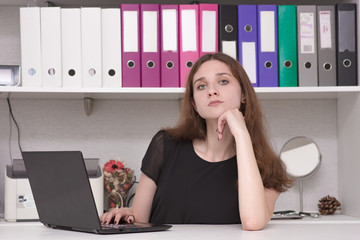 Portrait of beautiful brunette girl in office working with laptop at table