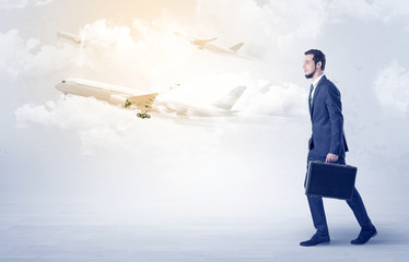 Obraz premium Elegant businessman going somewhere with briefcase and airplane on the background 