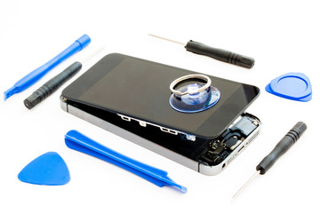 A damaged  mobile phone with touch screen removed and repair tools on an isolated white background