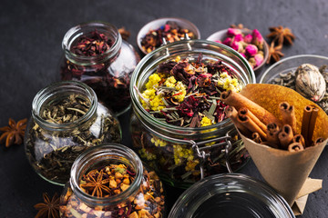 A set of various herbal and fruit teas in glass jars on a dark background. Medicinal herbs. A natural, eco product.