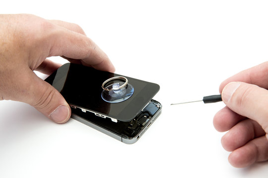 a POV image of a pair of hands holding a screwdriver and repairing a damaged mobile phone screen on an isolated white background