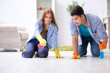 Naklejka premium Young family cleaning the house