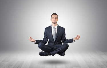 Businessman levitates and sitting in yoga position in an empty infinity space
