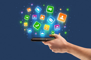 Businessman hand using phone with flying application icons around
