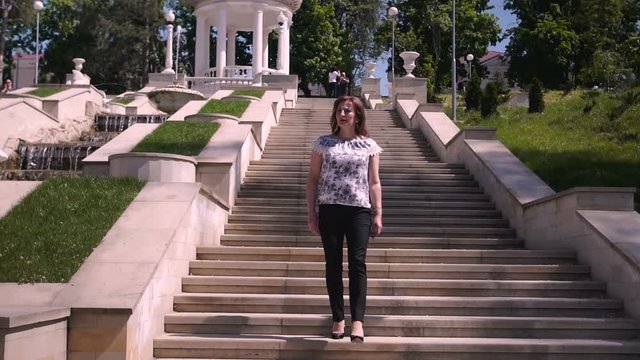 Young woman descends stone stairs in a sity parck