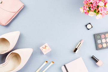 Fashion blogger workspace flat lay with pumps, cosmetics, purse, planner book and flowers.