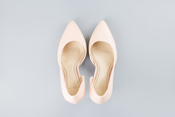 Pale pink female shoes close up on gray background.