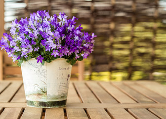 Purple flower in the ornamental pot on the wooden table in garden, copy space