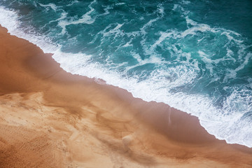 yellow sand beach and azure foam wave, shot from above, nature ocean background and texture with retro tinting