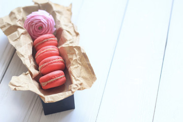 Colorful macaroons and flowers on table