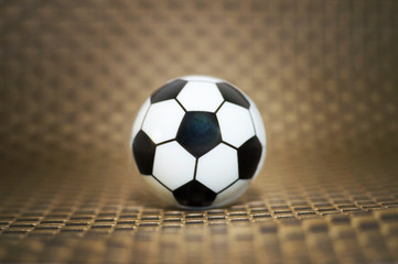 Fototapeta na wymiar A toy soccer ball on an artificial background. Concept of the game of football.