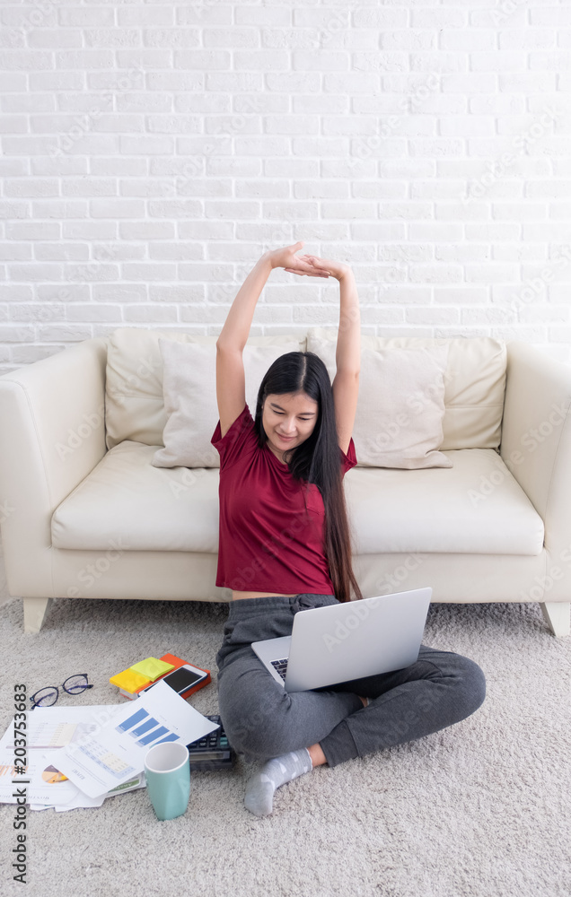 Poster asian female arm up to stretch oneself after use laptop computer to work in living room at home.woma
