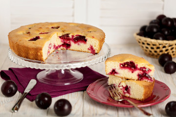 Homemade plum cake on a glass stand.