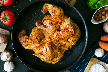 Chicken of tobacco in a frying pan. Finished chicken close-up, flat lay