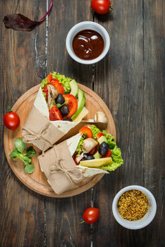 Healthy vegan lunch snack. Tortilla wraps with mushrooms, fresh vegetables on wooden background.