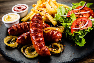 Grilled sausages, French fries and vegetables