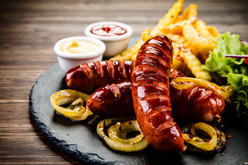 Grilled sausages, French fries and vegetables