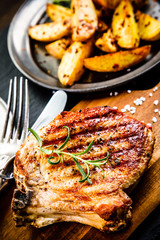 Grilled steak, French fries and vegetables on wooden background