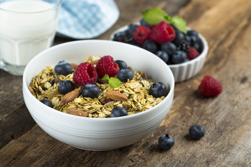 Homemade granola with fresh berries and mint, served with milk