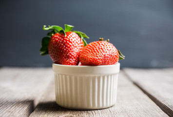 Ripe strawberries in small bowl on the rustic background. Selective focus.