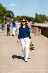 Teenage girl walking in city park with flowers