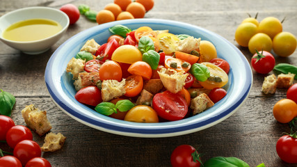 Homemade Panzanella, Tomato traditional Italian salad with red, yellow, orange cherry tomatoes, capers, basil and ciabatta croutons. summer healthy food.