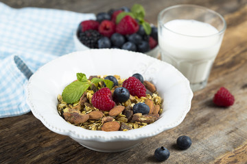 Homemade granola with fresh berries and mint, served with milk