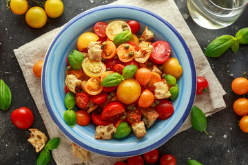 Homemade Panzanella, Tomato traditional Italian salad with red, yellow, orange cherry tomatoes, capers, basil and ciabatta croutons. summer healthy food.